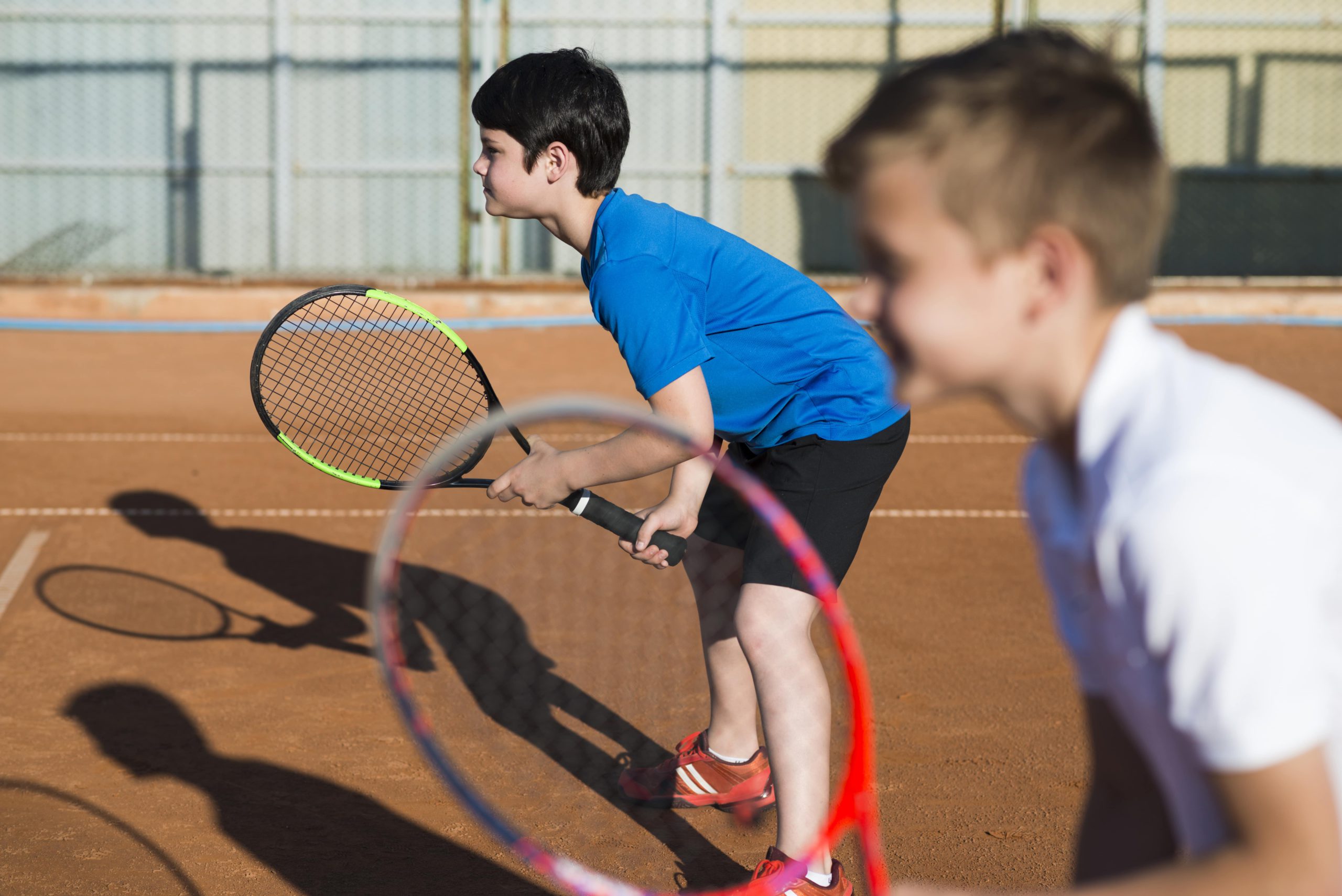 sideways-kids-playing-doubles-tennis-min